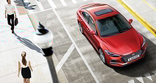 Side rear view of silver Elantra Sportdriving on the road in the city