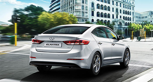 Side rear view of silver Elantra driving on the road in the city