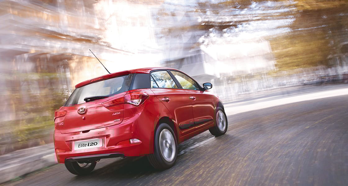 Right side rear view of driving red Elite i20 on the road