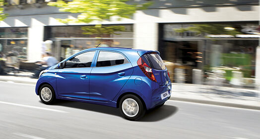 Side view of blue Eon driving fast on the street