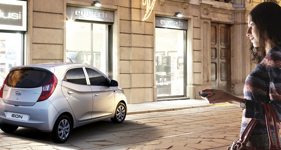 A woman approaching to silver Eon parked in front of the building