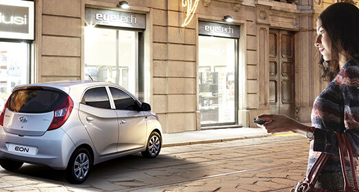 A woman approaching to silver Eon parked in front of the building