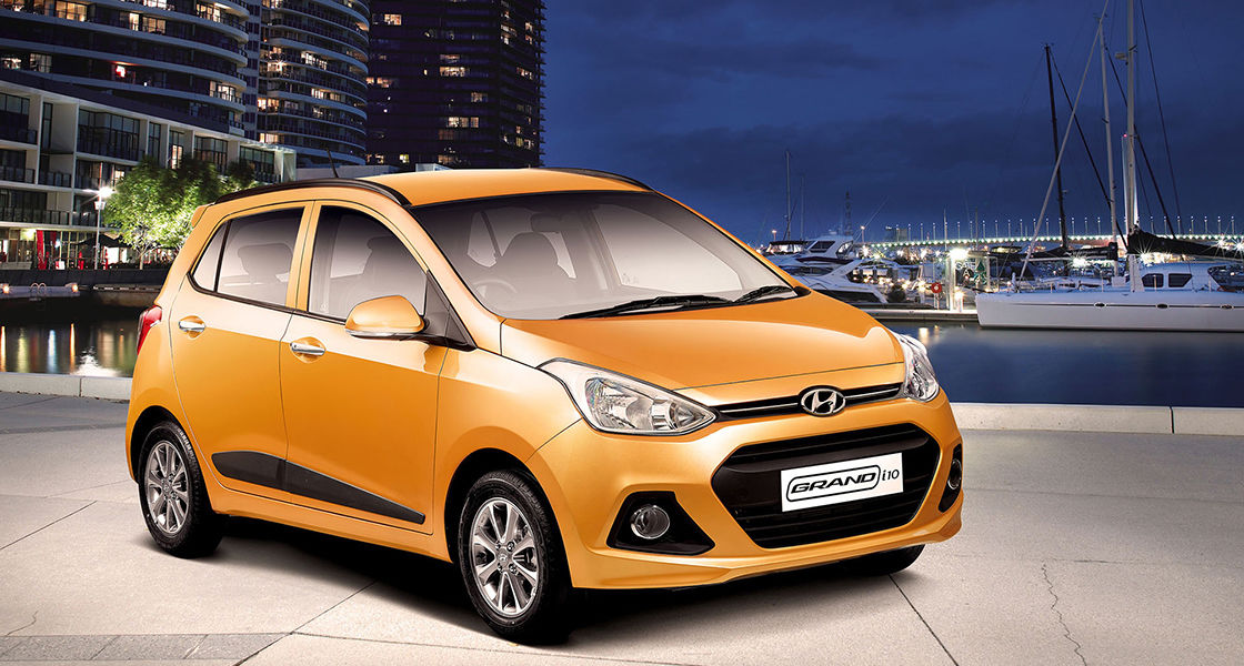 Side-front view of orange Grandi10 with lakeside view at night