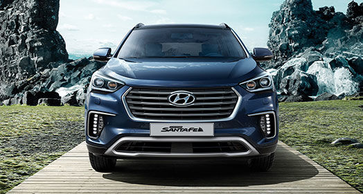 Front view of navy Grand Santafe parked with mountain background