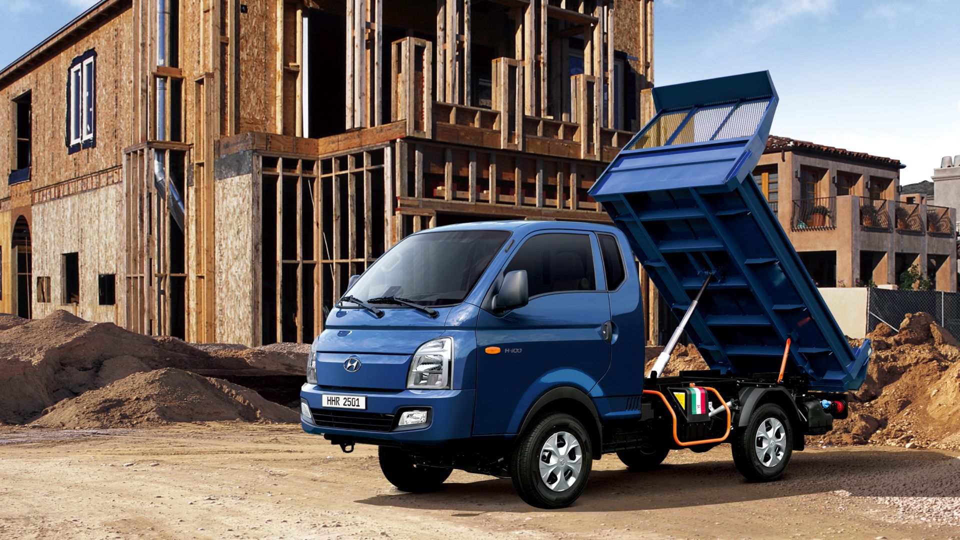 Front image of a dump truck with the dump bed raised up at a construction site