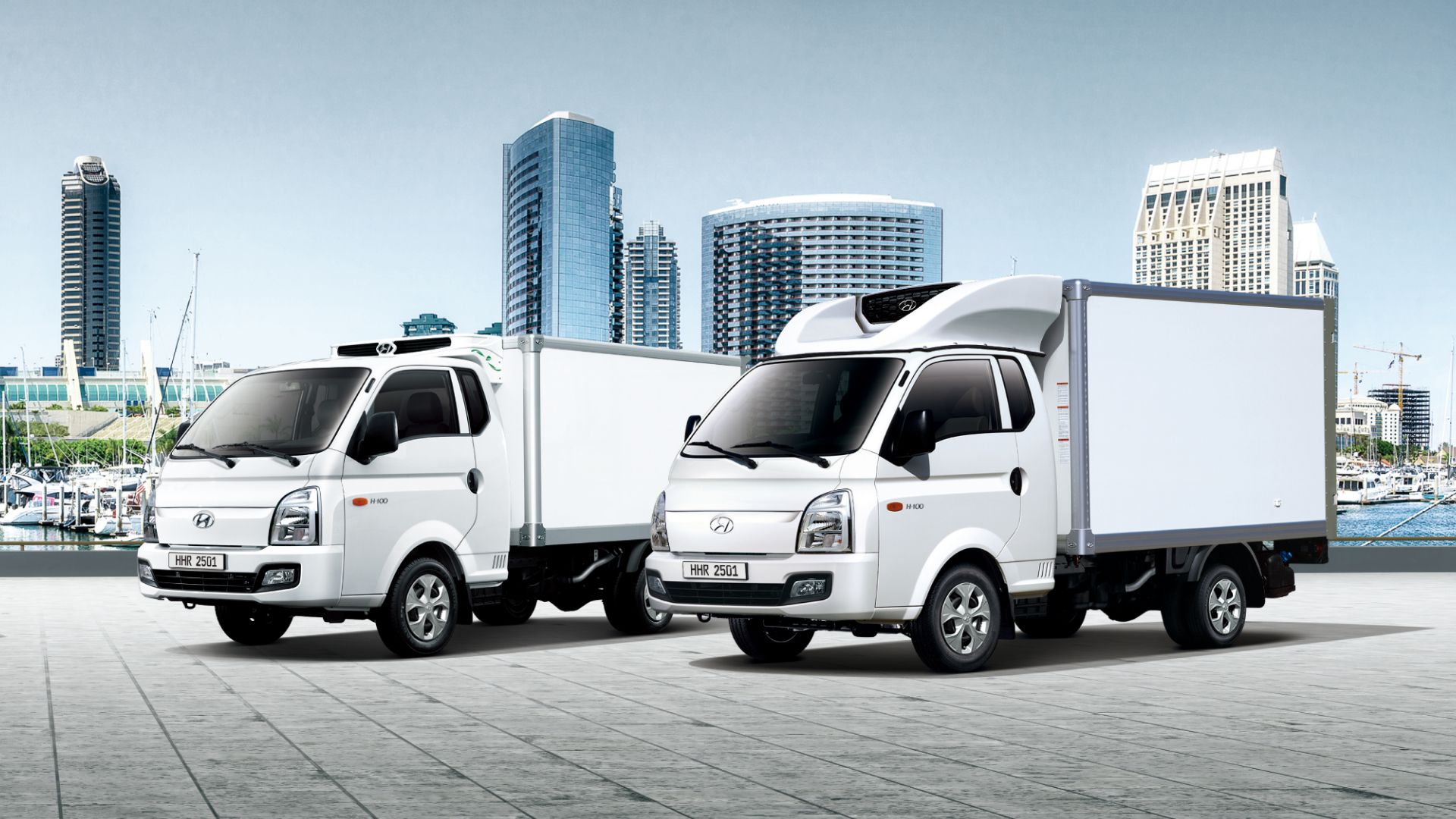 H-100 Freezer Trucks parked at the port with tall buildings in the background.