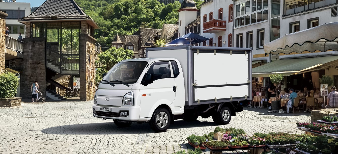 A Multi-purpose truck parked in an urban area with an outdoor terrace café