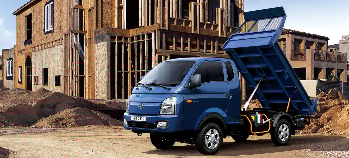 Front image of a dump truck with the dump bed raised up at a construction site