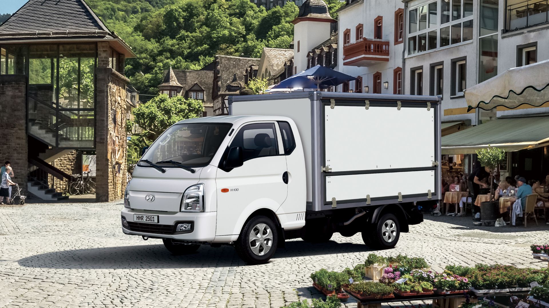 A Multi-purpose truck parked in an urban area with an outdoor terrace café