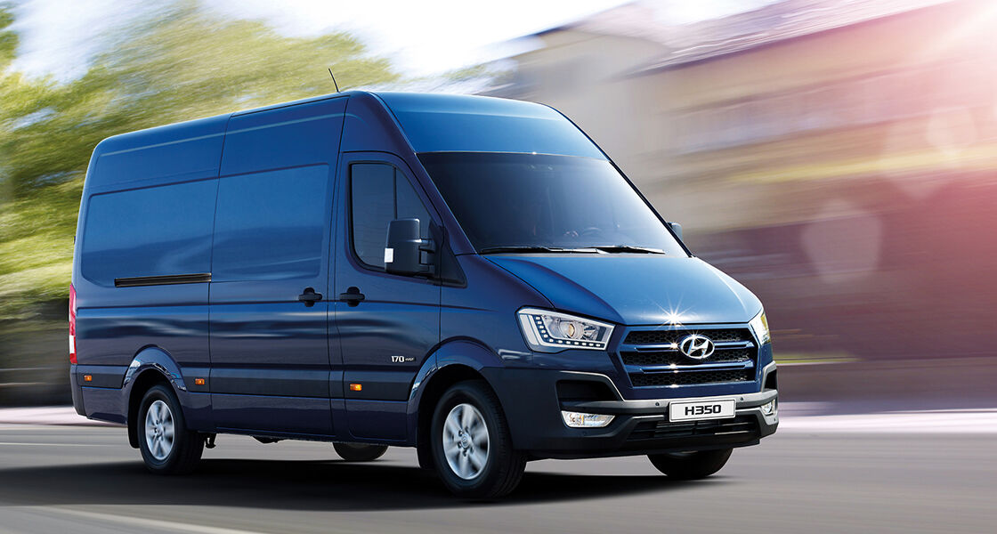 Side front view of blue H350 driving fast on the road