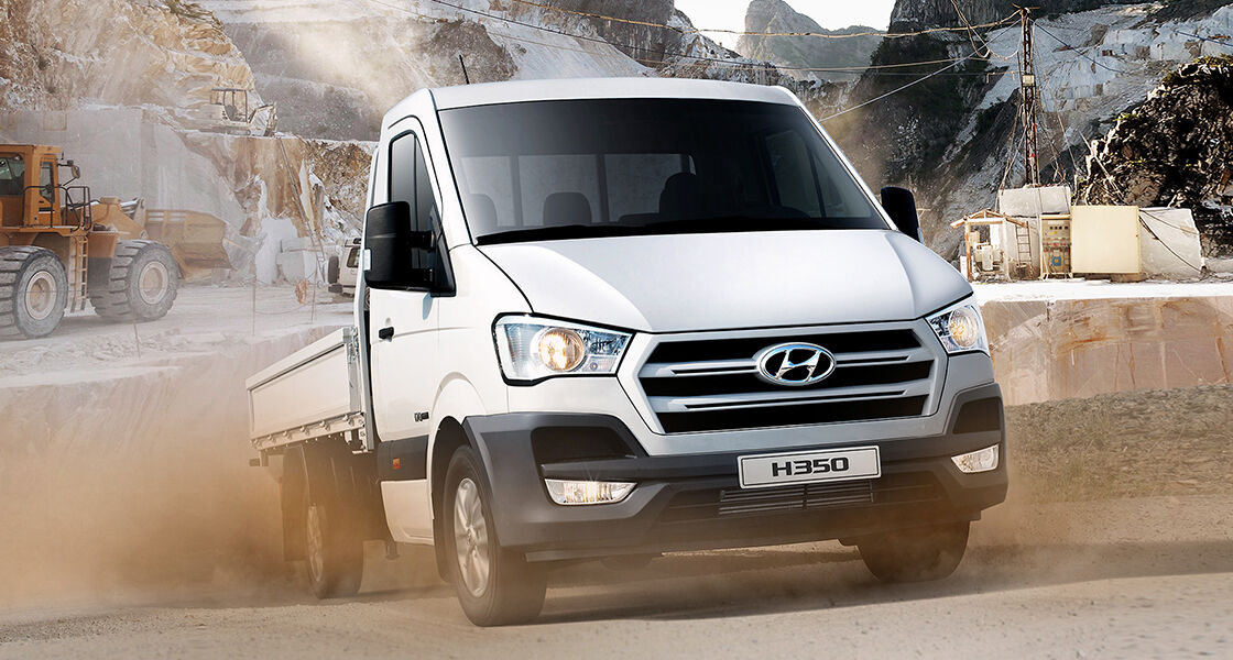 Side front view of white H350 driving roughly on the road