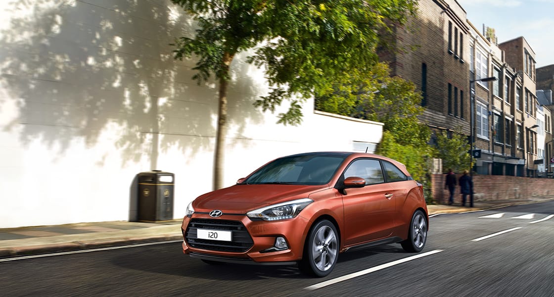 Side view of orange i20 coupe driving on the street
