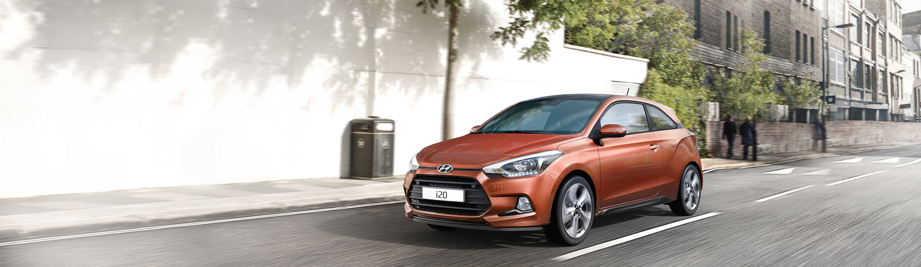 Side front view of orange i20 Coupe driving on the road