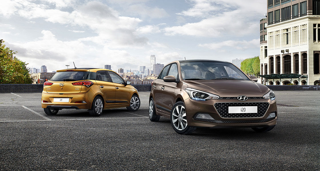Front side view of brown i20 in front and side-rear view of mandarin orange i20 parked behind with skyline view