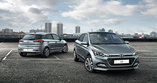 Front side view of dark gray i20 in front and side-rear view of dark gray i20 parked behind with skyline view