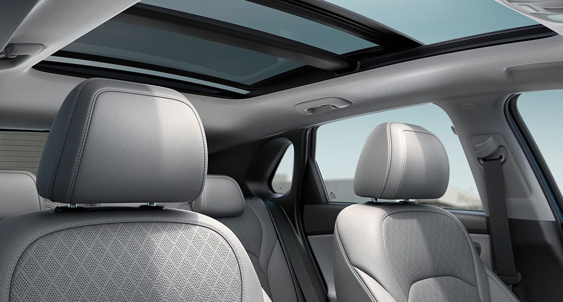 صورة من زاوية منخفضة لمقصورة داخلية بلون بيج وتظهر فتحة السقف مفتوحة في يوم صحو