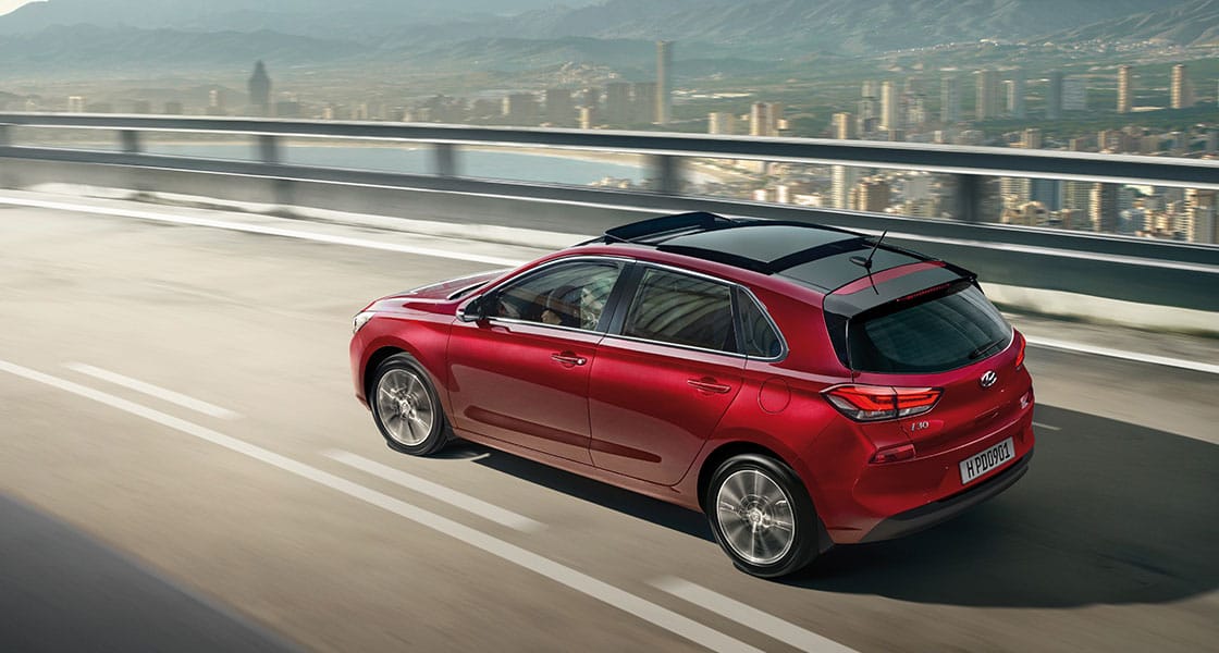 منظر خلفي للجانب الأيسر لسيارة آي30 الحمراء تسير على الطريق