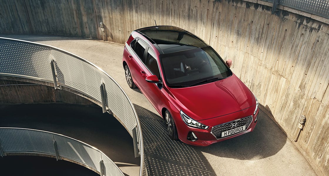 منظر أمامي للجانب الأيمن لسيارة آي30 الحمراء تسير على الطريق الصاعد