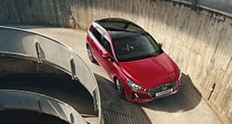 منظر أمامي للجانب الأيمن لسيارة آي30 الحمراء تسير على الطريق الصاعد