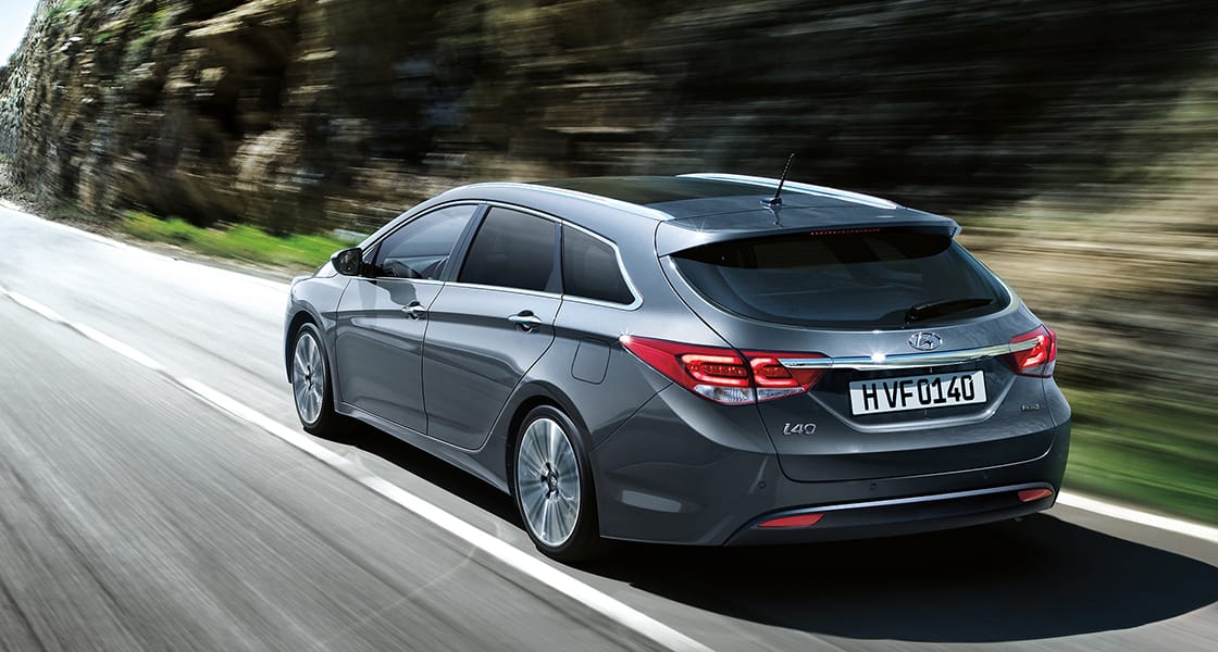 Side rear view of dark gray i40 driving fast on the mountainous road
