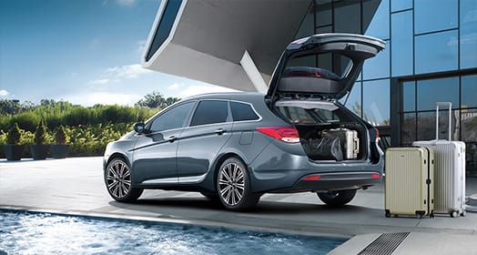 Side rear view of dark gray i40 with trunk door opened next to swimming pool