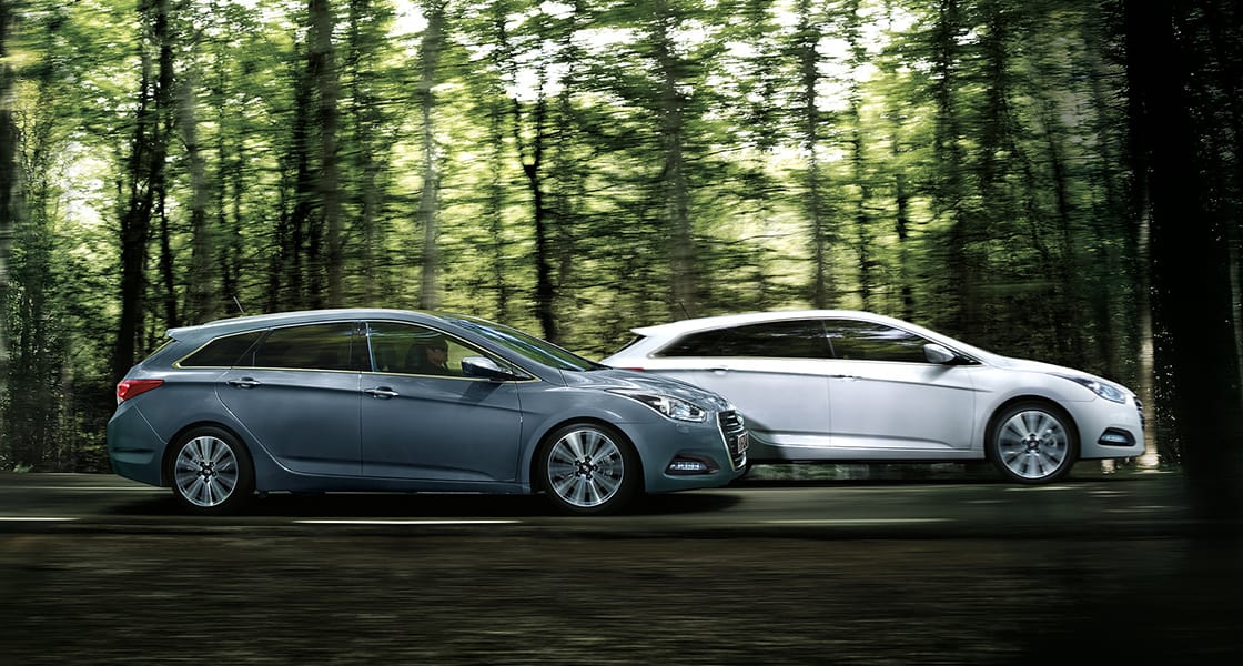 Side view of white and dark gray blue i40s driving in the forest