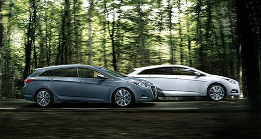 Side view of white and dark gray blue i40s driving in the forest