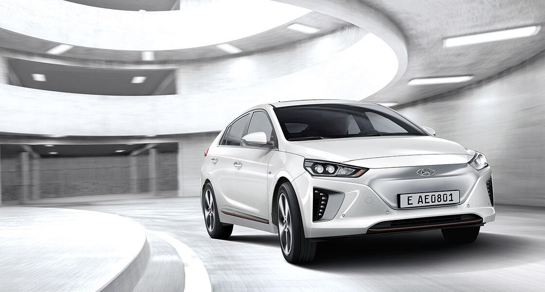Side front view of white Ionic hybrid driving in the car park tower