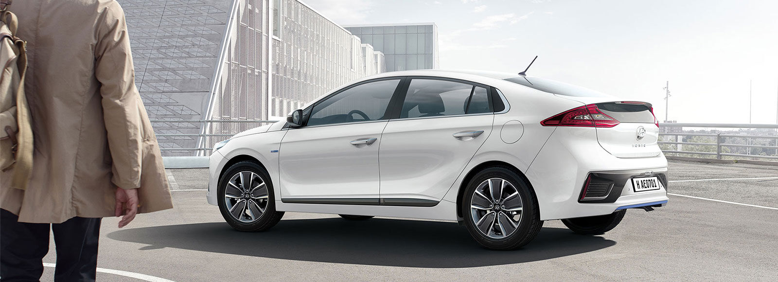 A man approaching to white Ioniq Hybrid parked outdoor