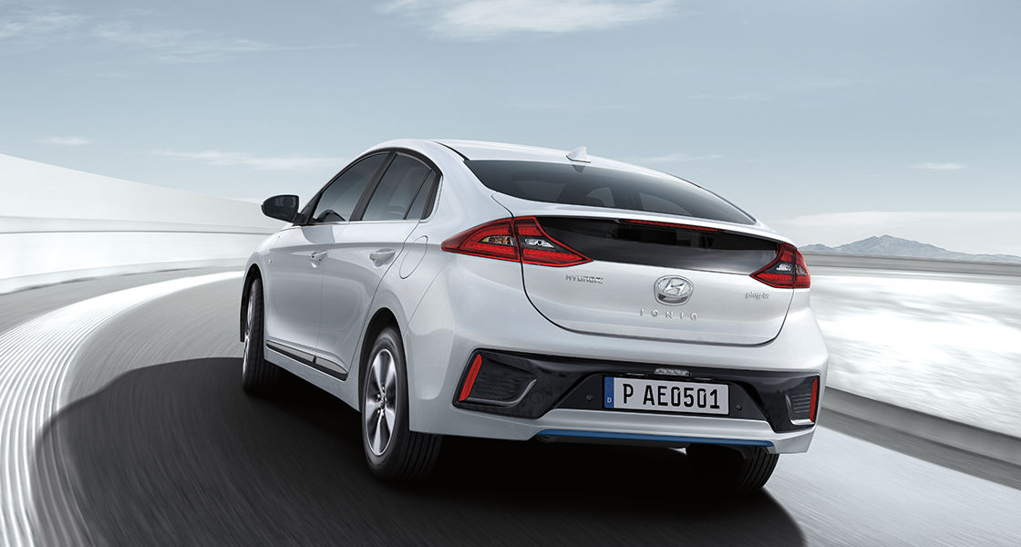 Side rear view of white Ioniq plug-in hybrid driving on the road.