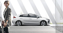 Side view of white Ioniq hybrid and a couple standing in front