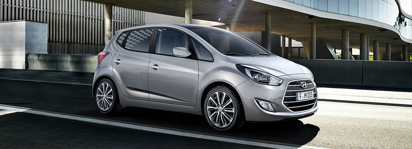 Side front view of light gray ix20 with person cycling beside