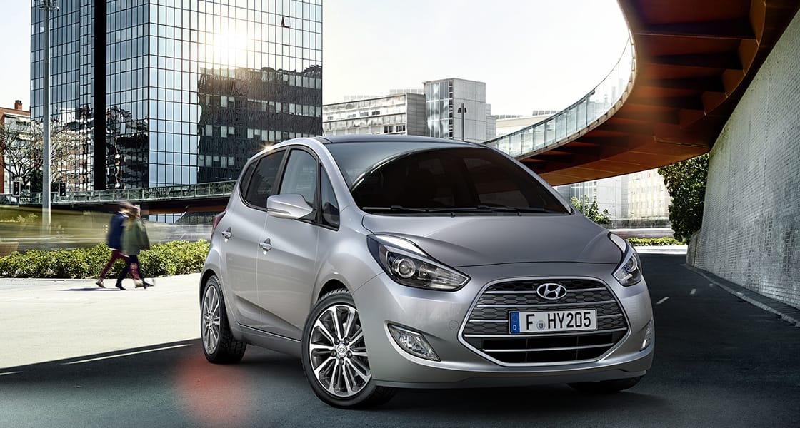 Side front view of light gray ix20 parked next to the wall of building