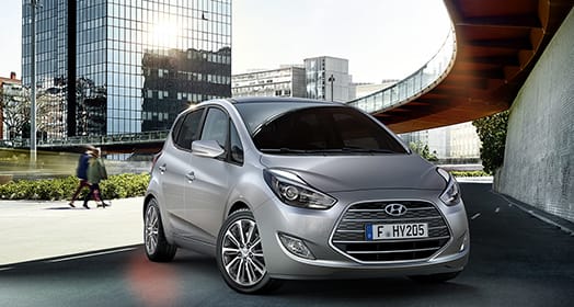 Side front view of light gray ix20 parked next to the wall of building