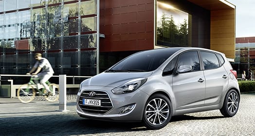 Side front view of light gray ix20 with person cycling beside