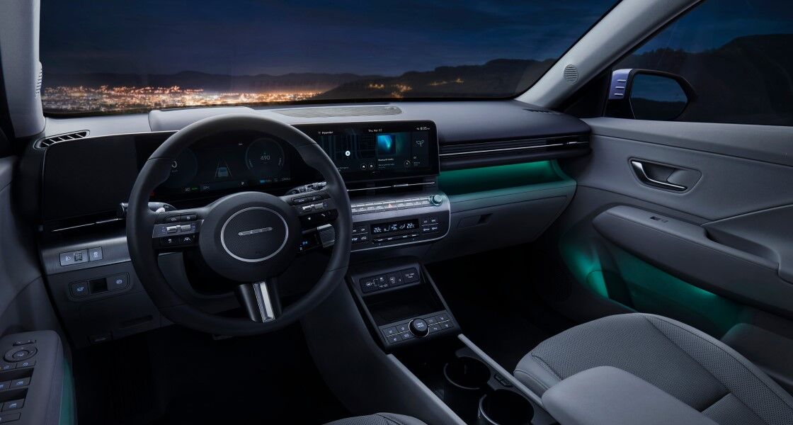 A view of a brightly lit city from The all-new KONA parked on a dark hill.