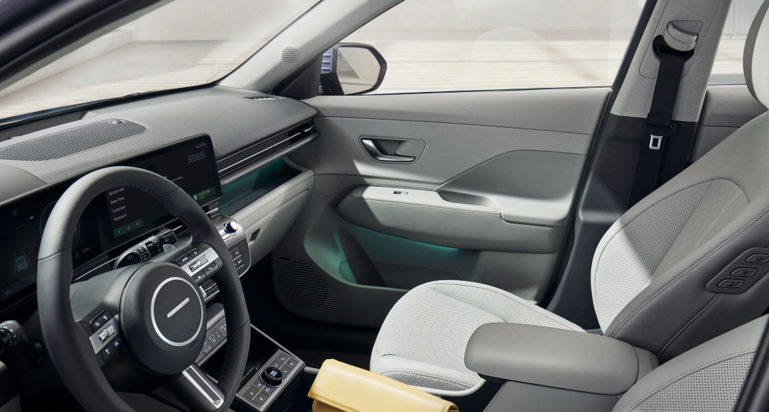 منظر من الداخل للسيارة كونا الجديدة كليًا من خلال نافذة السائق. يمكن رؤية عجلة القيادة ومقعد الراكب.