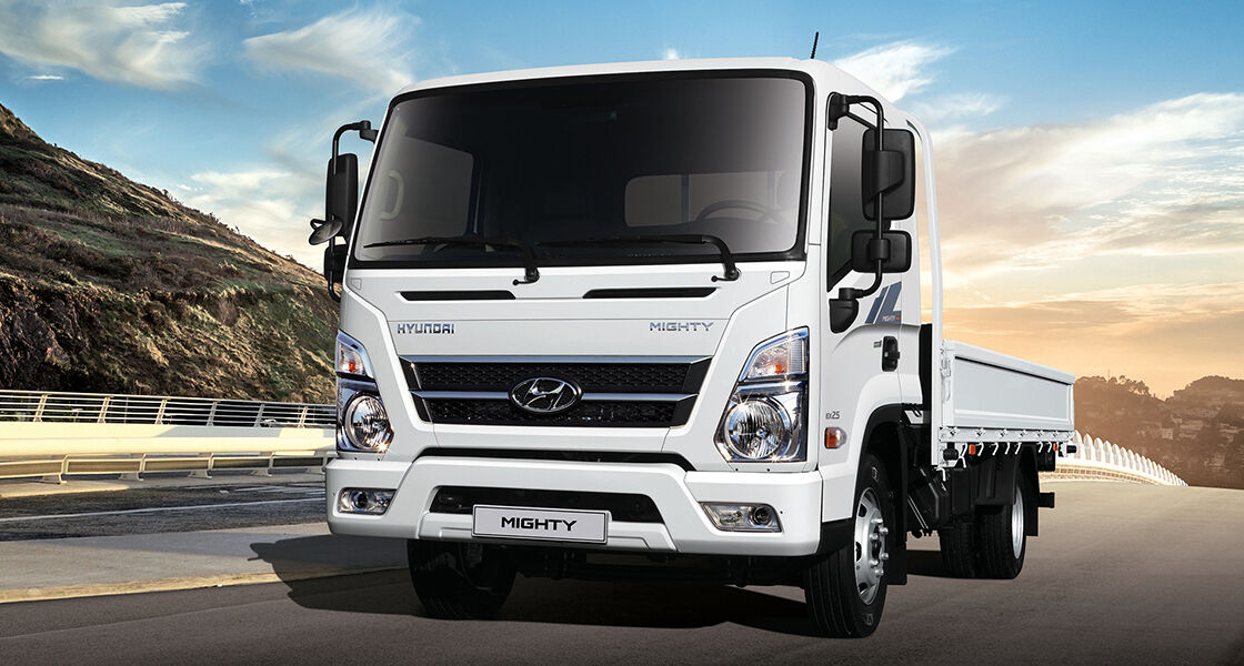 Front view of white Mighty driving on the road in sunset time