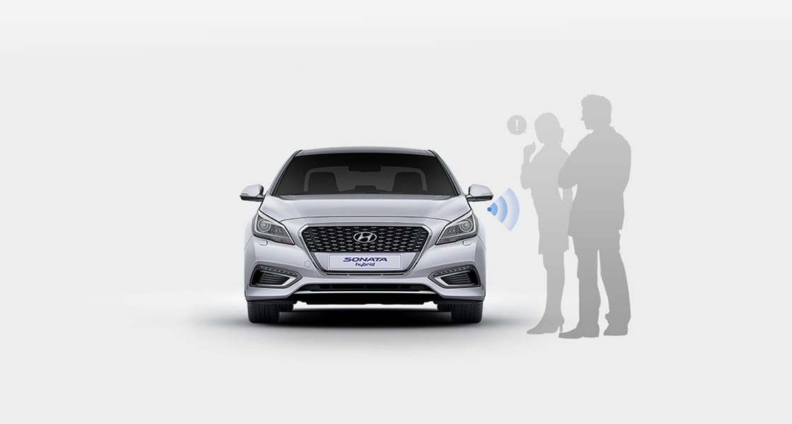 Two silhouette of people standing next to front view of silver Sonata Hybrid