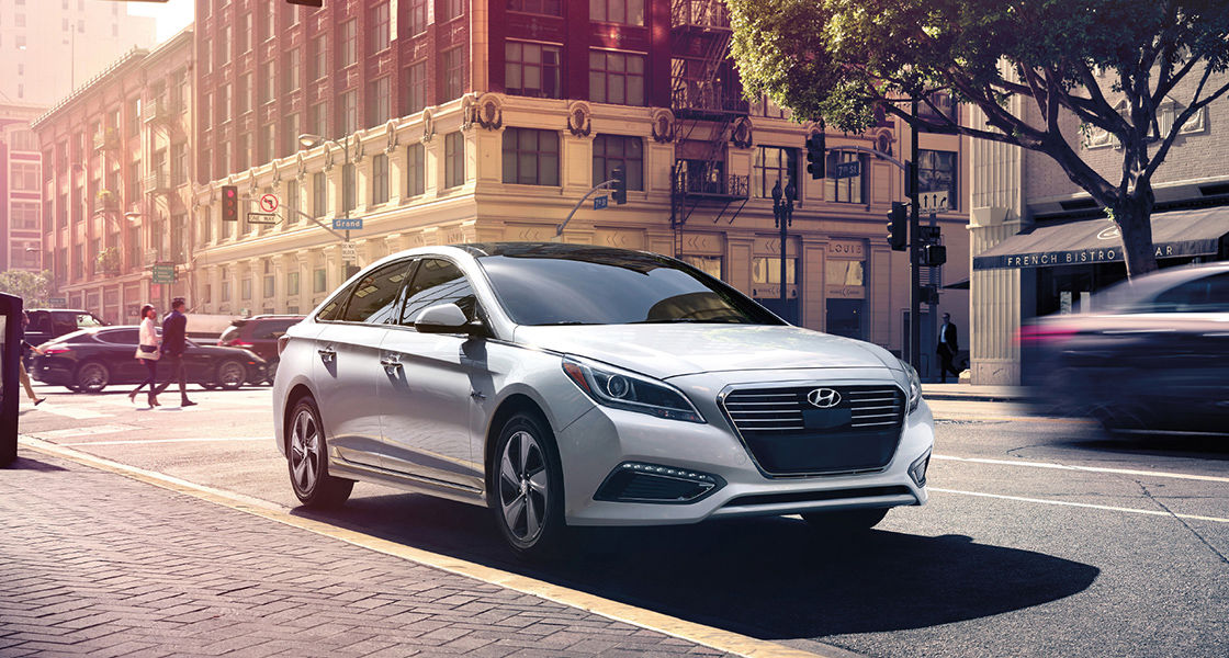Side front view of white Sonata Plug-in Hybrid driving on the street