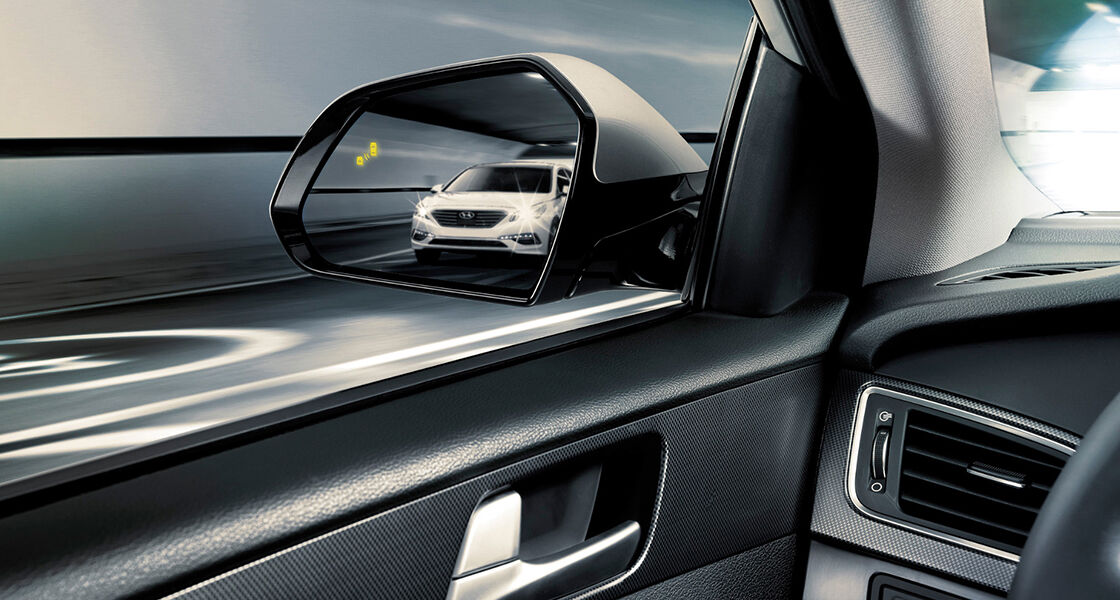 The view of white Sonata approaching reflected on the driver side mirror