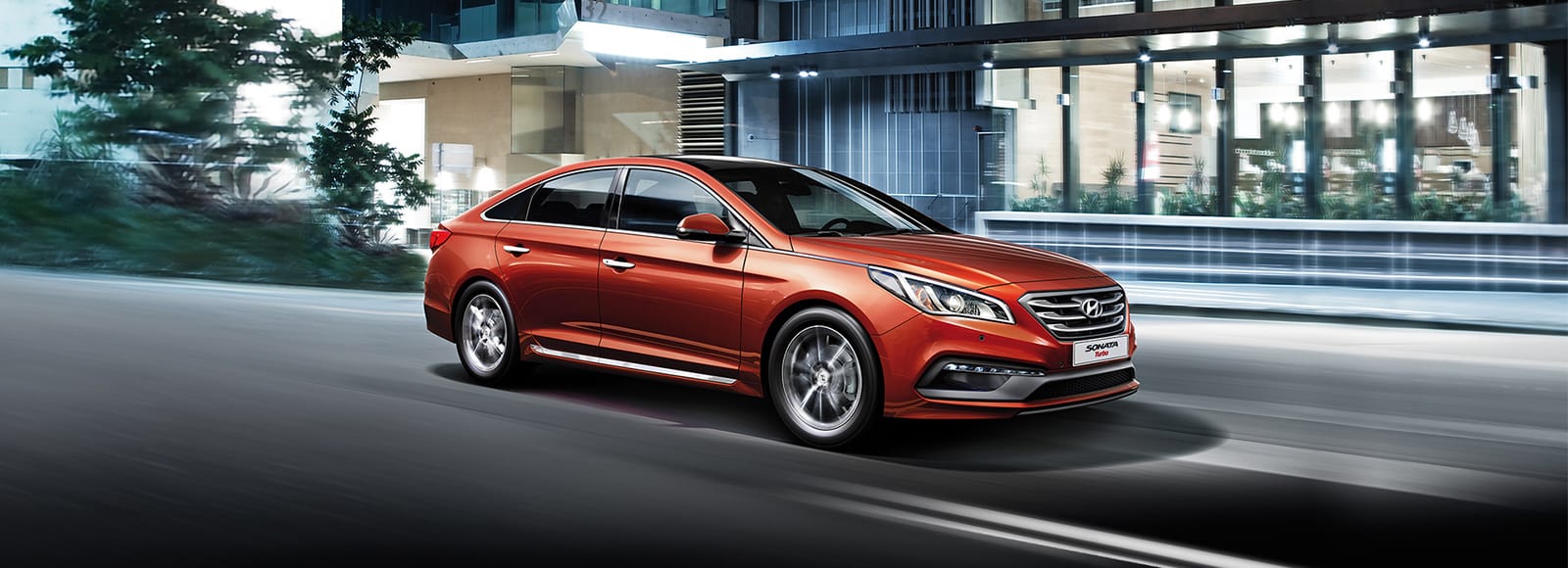 Side view of red Sonata Turbo driving on the road in the evening