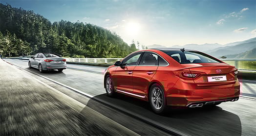 Light gray Sonata Turbo in front and red Sonata Turbo driving on the road on a sunny day