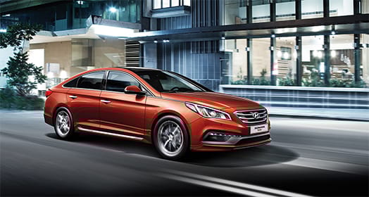 Side view of red Sonata Turbo driving on the street at night