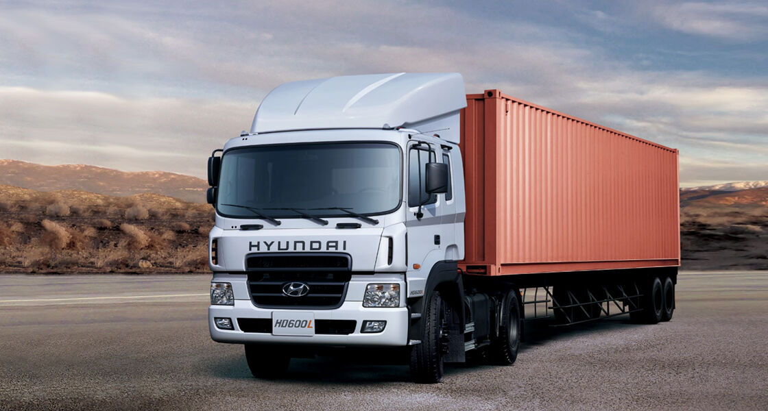 image of tracktor trailing a huge container box out of warehouse