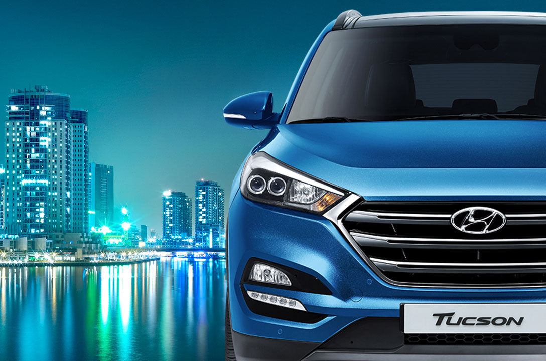 Front view of blue Tucson with night city view