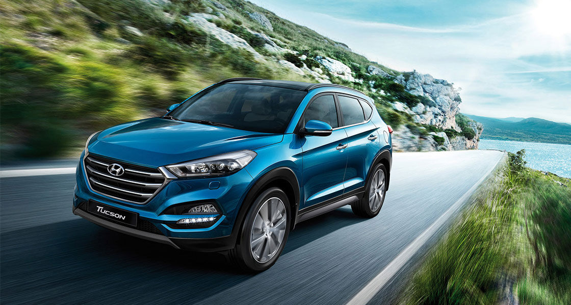 Left side front view of light blue Tucson driving on the mountainous road