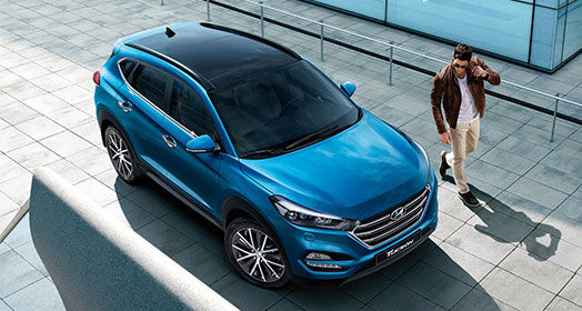 Sky view of a man standing next to blue Tucson