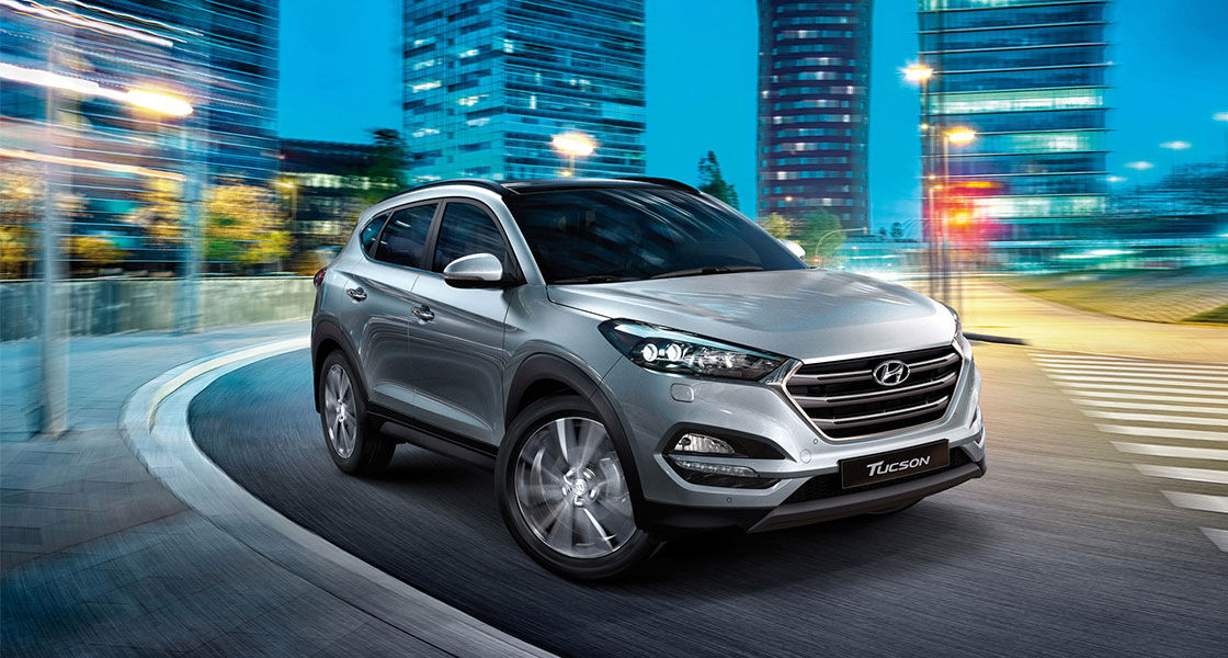 Right side front view of silver Tucson on the road in the city at a night