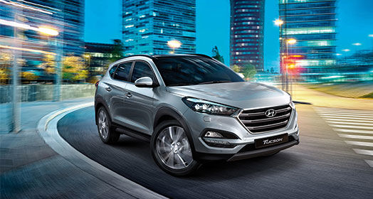 Right side front view of silver Tucson on the road in the city at a night